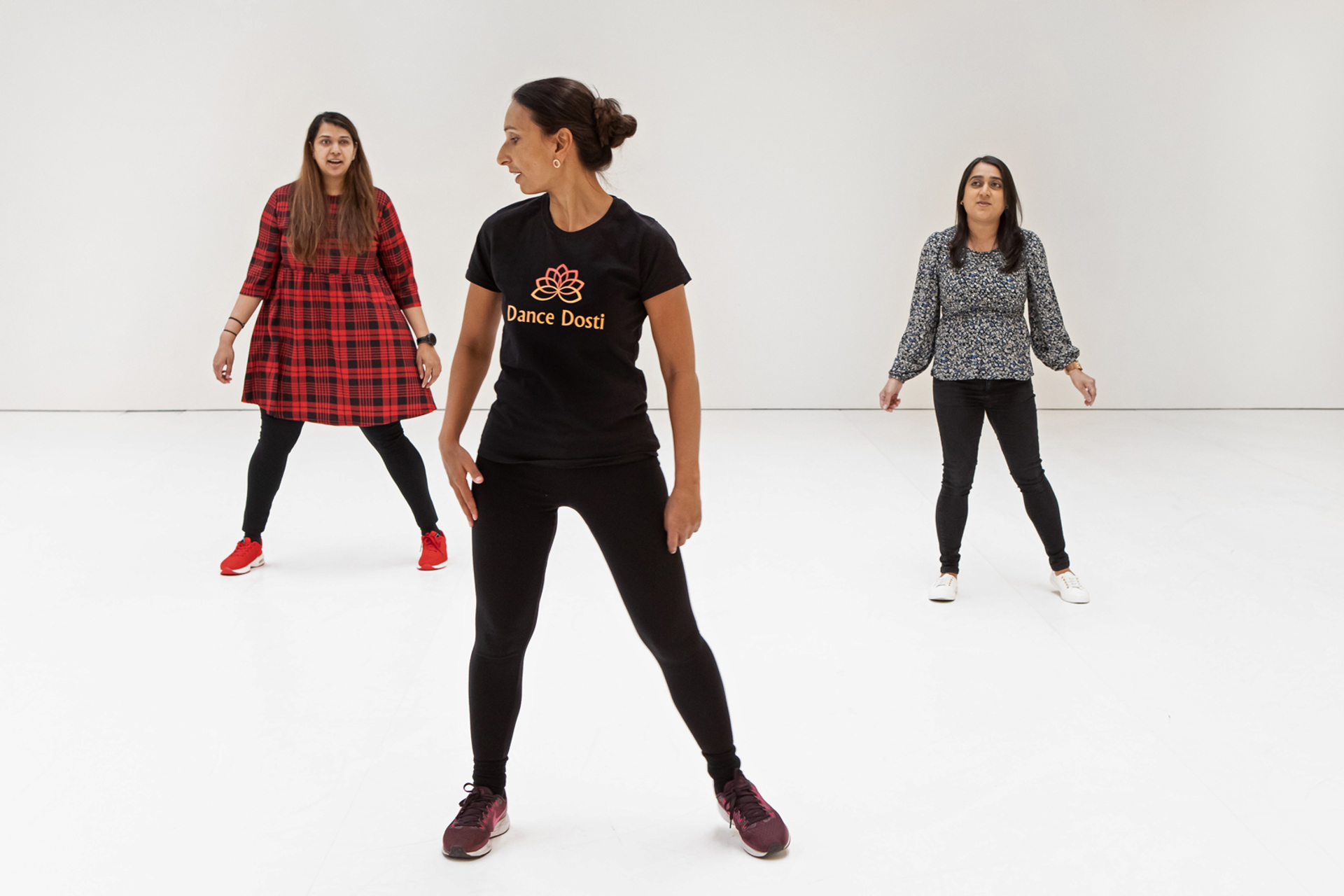 Three global majority female dancers. one standing front and centre with two further back each side. All wearing casual clothes on a white background Three global majority female dancers. one standing front and centre with two further back each side. All wearing casual clothes on a white background