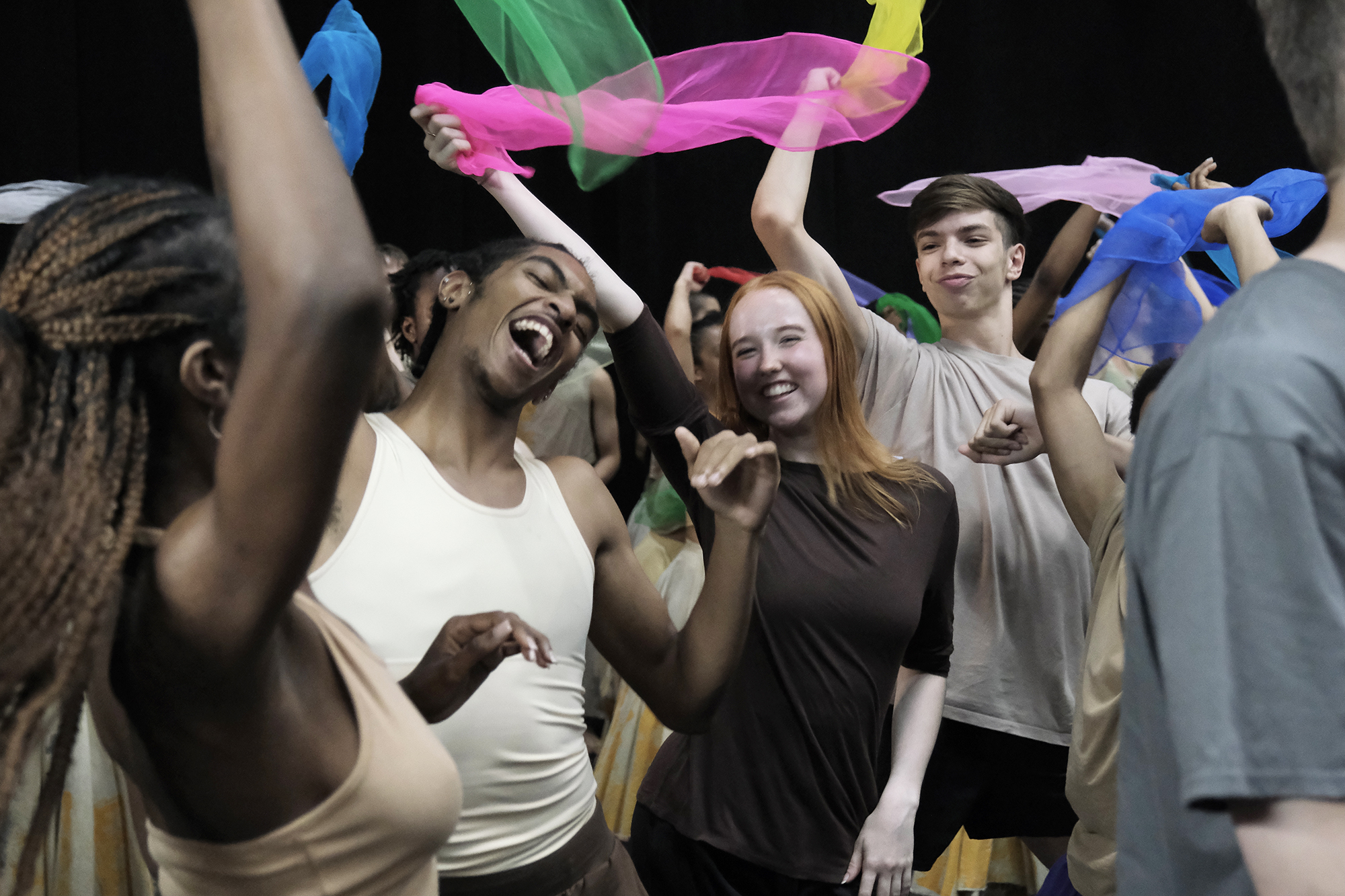 young people mixed genders and races dancing together with big smiling faced waving brightly colour scarfs. young people mixed genders and races dancing together with big smiling faced waving brightly colour scarfs.